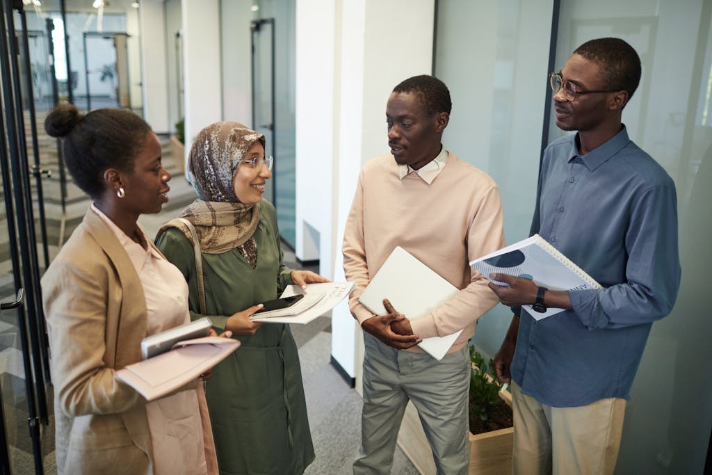 A group of multicultural colleagues discussing work materials in a modern office setting.