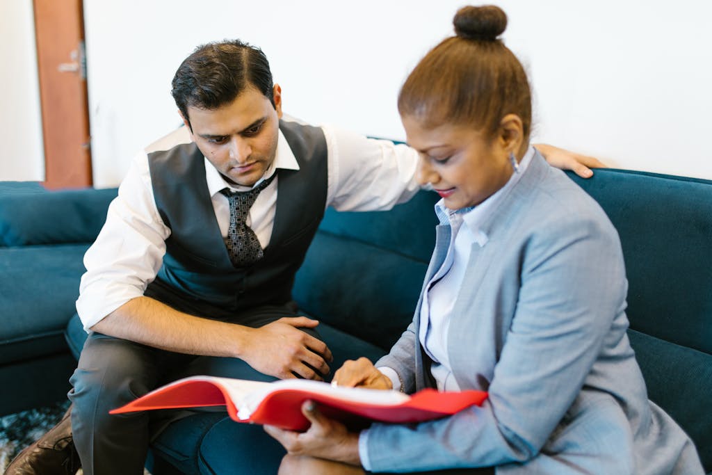 A man and woman in business attire reviewing documents together in an office setting.