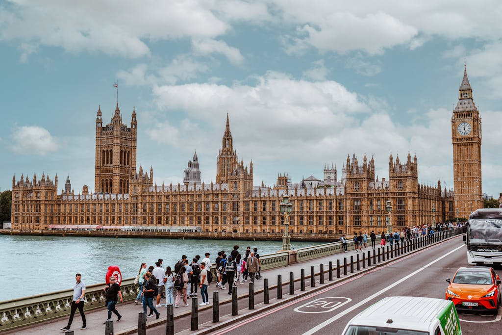 A vibrant view of Westminster Palace and Big Ben from Thames showing tourists and traffic.