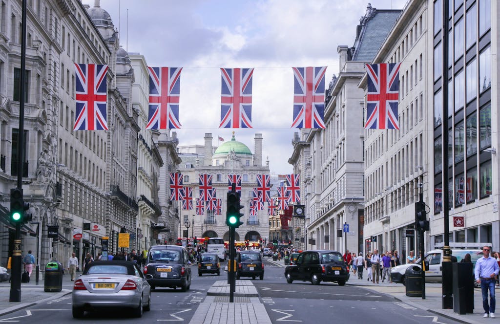Busy London street adorned with Union Jack flags, showcasing classic architecture and bustling city life.