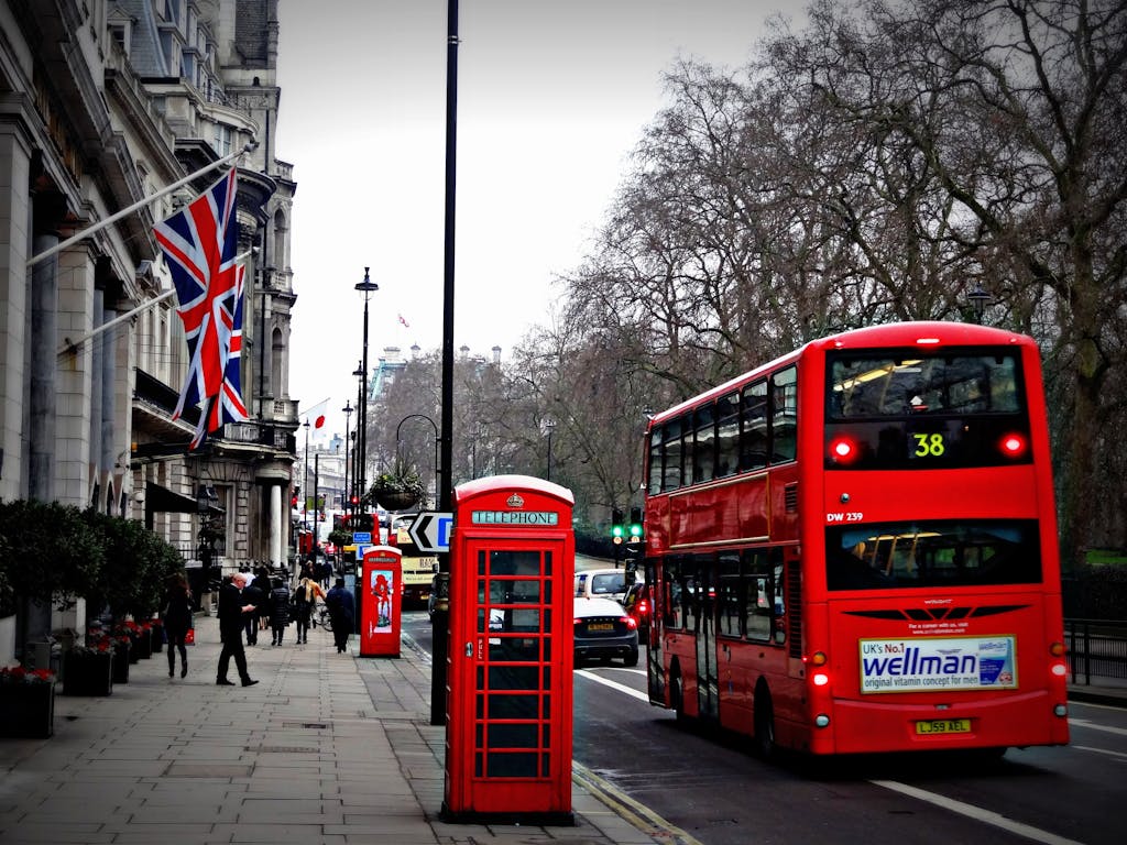 Classic London scene featuring a red double-decker bus and iconic phone booth on a busy city street.