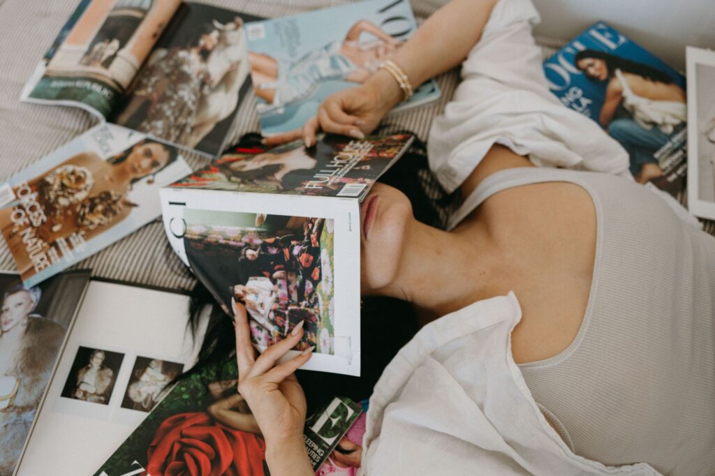 A woman reads fashion magazines, evoking a relaxing lifestyle and fashion mood.